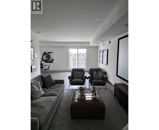 A living room with a grey couch, a brown coffee table, and a large window.