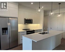 A modern kitchen with a white countertop and stainless steel appliances.