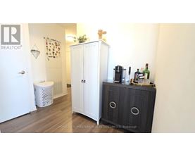A white cabinet with a black door is in a room with a white wall.