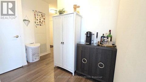 A white cabinet with a black door is in a room with a white wall.