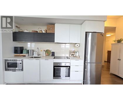 A modern kitchen with white cabinets and stainless steel appliances.