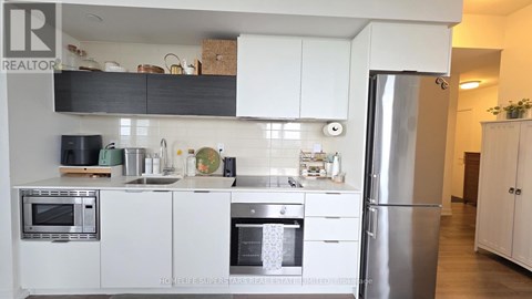 A modern kitchen with white cabinets and stainless steel appliances.