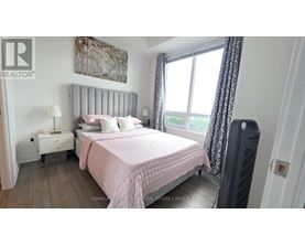 A bedroom with a pink bedspread and a large window with curtains.