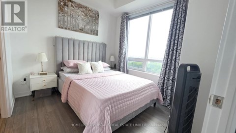 A bedroom with a pink bedspread and a large window with curtains.
