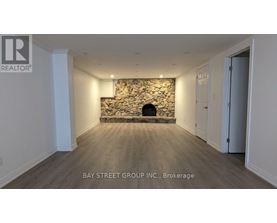 A room with a stone fireplace and wooden flooring.