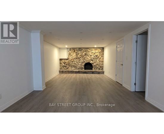 A room with a stone fireplace and wooden flooring.