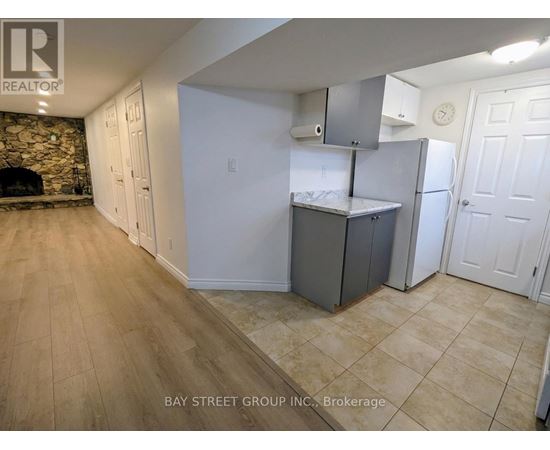 A kitchen area with a refrigerator, cabinets, and a countertop.