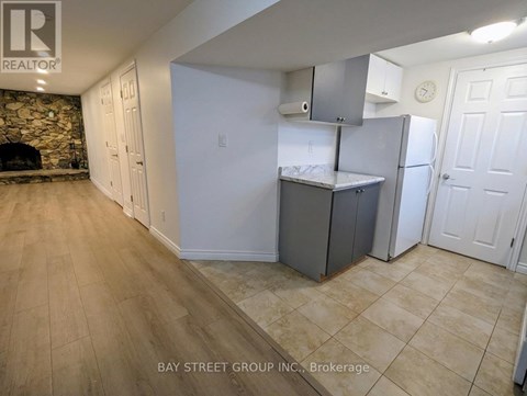 A kitchen area with a refrigerator, cabinets, and a countertop.
