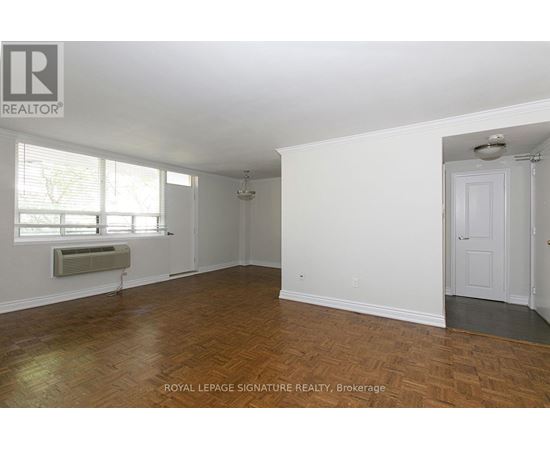 A room with wooden flooring and white walls, with a door on the right side.