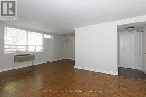 A room with wooden flooring and white walls, with a door on the right side.