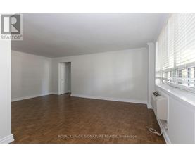 A room with wooden flooring and white walls, with a window on the right side.