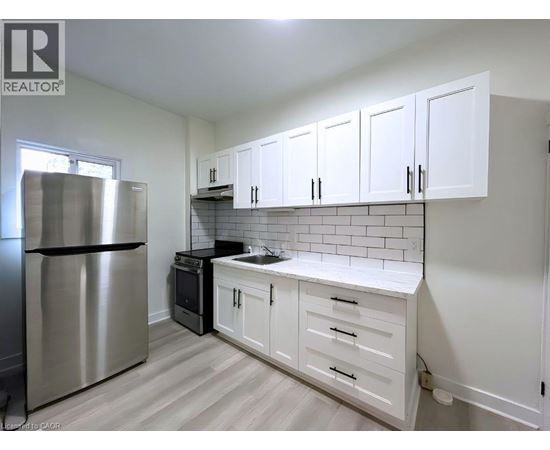 A kitchen with white cabinets and a stainless steel refrigerator.