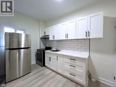 A kitchen with white cabinets and a stainless steel refrigerator.
