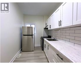 A kitchen with white cabinets and a stainless steel refrigerator.