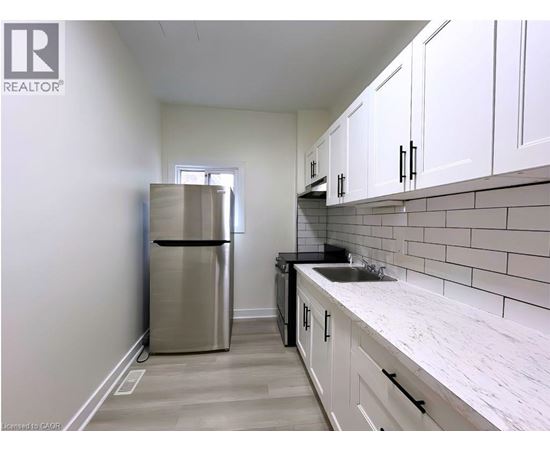A kitchen with white cabinets and a stainless steel refrigerator.
