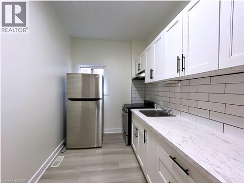 A kitchen with white cabinets and a stainless steel refrigerator.