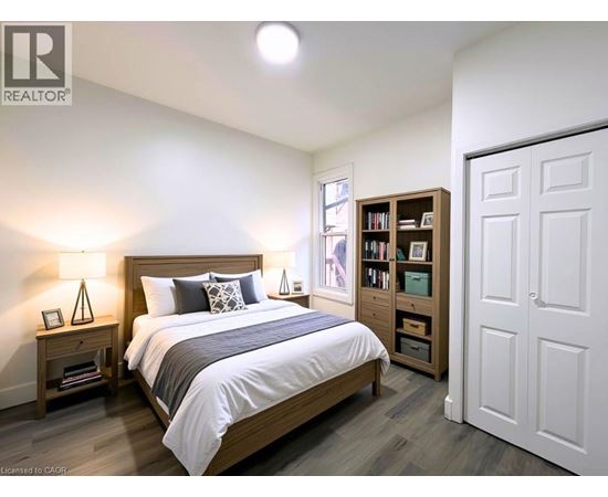 A bedroom with a large bed, a nightstand with a lamp, and a bookshelf.