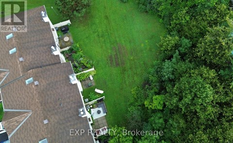 A bird's eye view of a house with a brown roof and a green lawn.