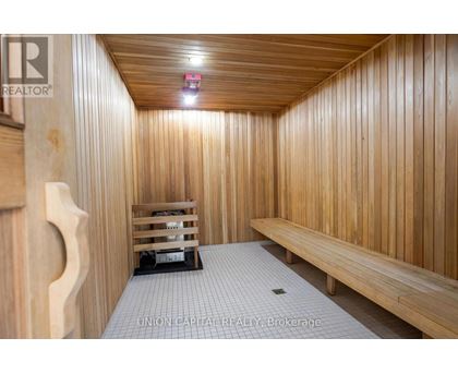 A wooden sauna room with benches and a light on the ceiling.
