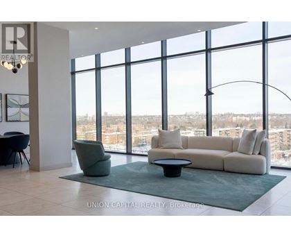 A living room with a couch, chair, and large windows overlooking a cityscape.