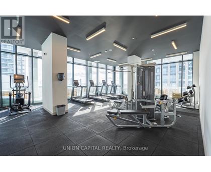 A gym with a row of treadmills and a row of stationary bikes.