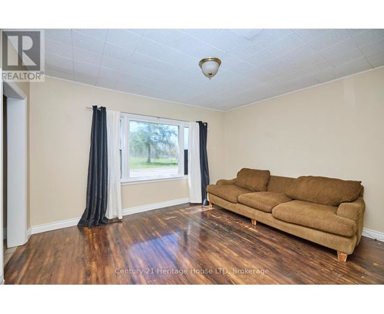 A living room with a brown couch and a window with curtains.
