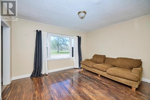 A living room with a brown couch and a window with curtains.