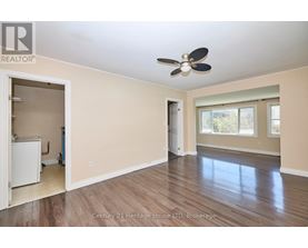 A spacious room with a ceiling fan and hardwood flooring.