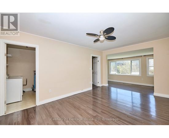 A spacious room with a ceiling fan and hardwood flooring.