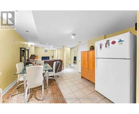 A kitchen with a white fridge and a dining table with chairs.