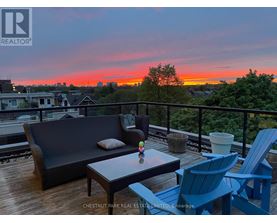 A balcony with a couch, chairs and a table with a sunset in the background.