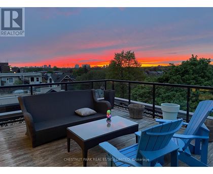 A balcony with a couch, chairs and a table with a sunset in the background.
