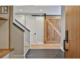 A hallway with a wooden door and a staircase.