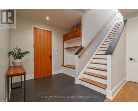 A wooden door is in a white hallway.