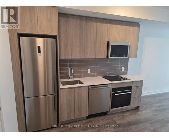 A modern kitchen with a stainless steel refrigerator and wooden cabinets.