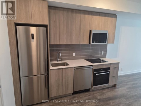 A modern kitchen with a stainless steel refrigerator and wooden cabinets.
