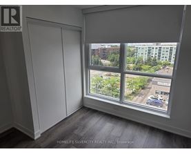 A room with a large window showing a view of a parking lot and buildings outside.