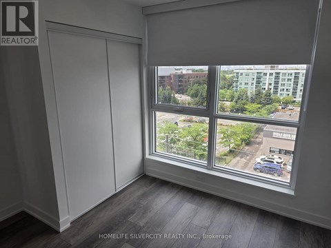 A room with a large window showing a view of a parking lot and buildings outside.