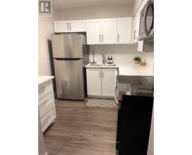 A kitchen with a stainless steel refrigerator, white cabinets, and a black dishwasher.