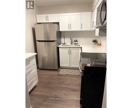 A kitchen with a stainless steel refrigerator, white cabinets, and a black dishwasher.