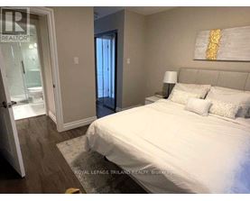A bedroom with a large bed and a painting on the wall.