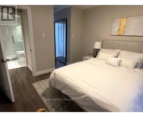 A bedroom with a large bed and a painting on the wall.
