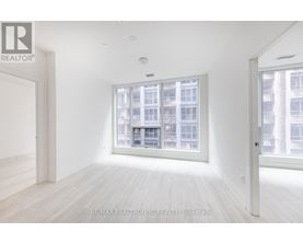 A white room with a large window and wooden flooring.