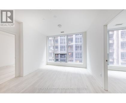 A white room with a large window and wooden flooring.