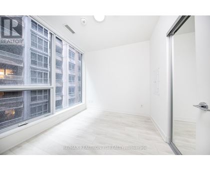 A white room with a window overlooking a building with the logo RE/MAX Realty YC Realty Brokerage.