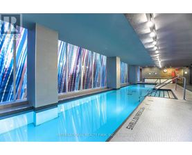 A swimming pool inside a building with a glass wall on one side.