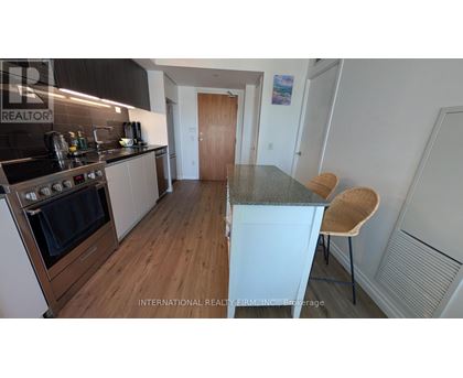 A modern kitchen with a wooden floor and a stove top oven.