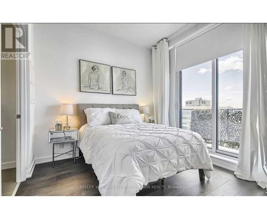 A bedroom with a large bed and a window overlooking a cityscape.