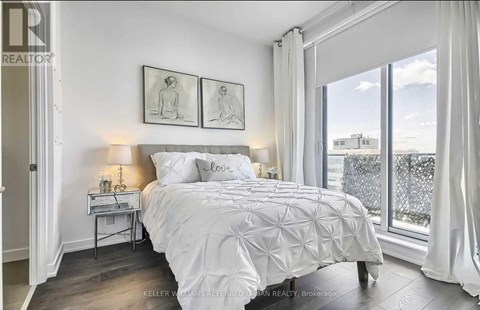 A bedroom with a large bed and a window overlooking a cityscape.
