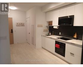 A kitchen with white cabinets and black countertops.